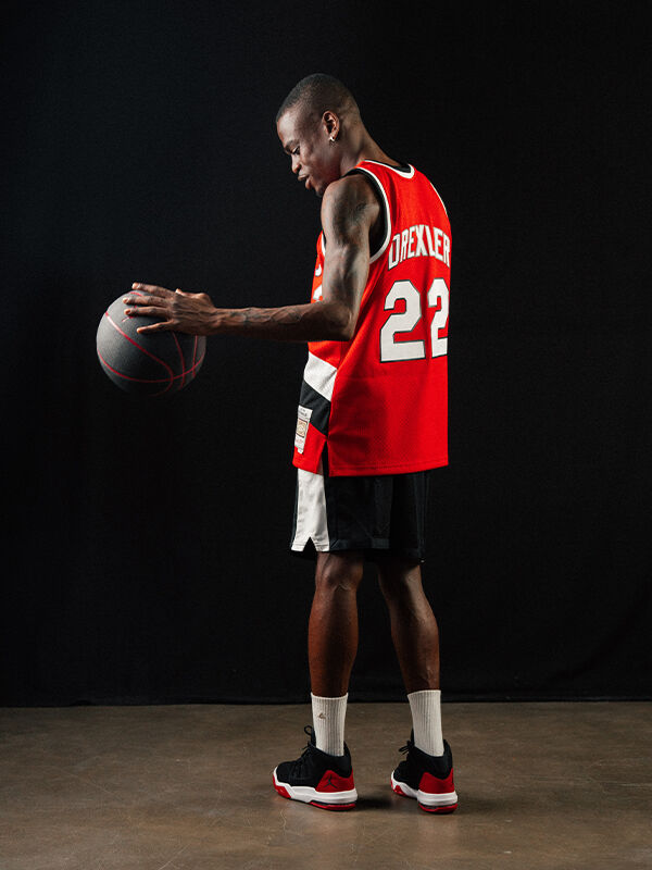 Basketballspieler mit 22 Drexler Trikot, Jordanshorts, -schuhen und -basketball